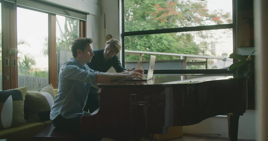 Two men are playing the piano indoors
