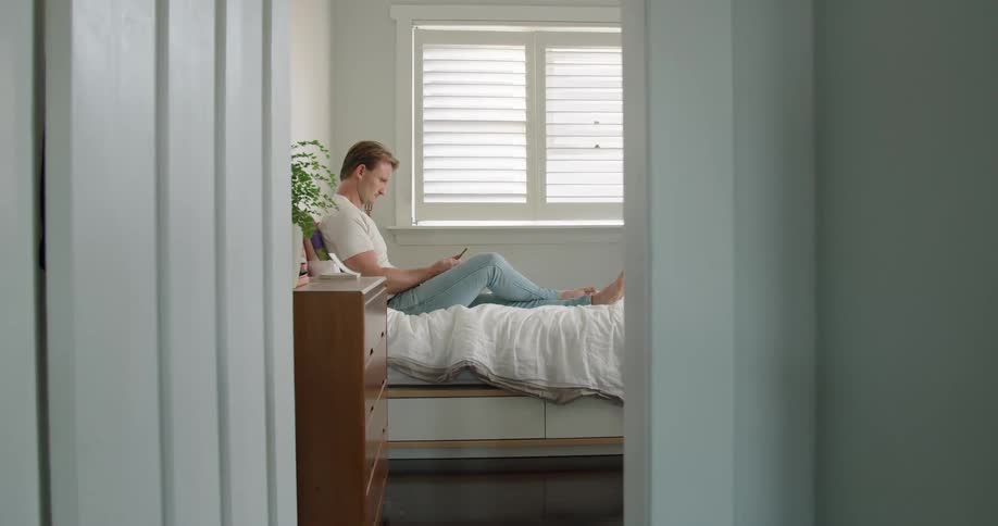 A man laying on a bed reading and relaxing