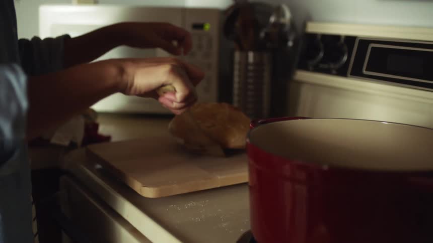 A woman at home takes some food out of a pot