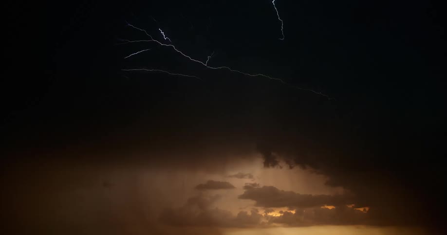 Lightning forks and flashes across the sky in dark clouds in the evening