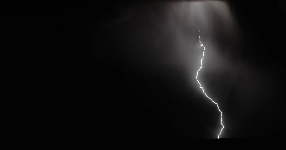 Lightning streaking arcs flashing over the silhouette of black clouds at night