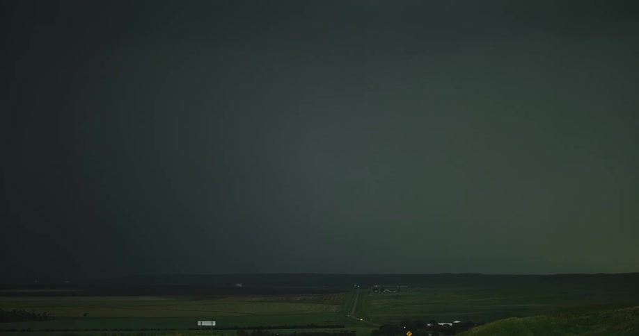 Lightning flashing in a dark cloudy sky over a rural area