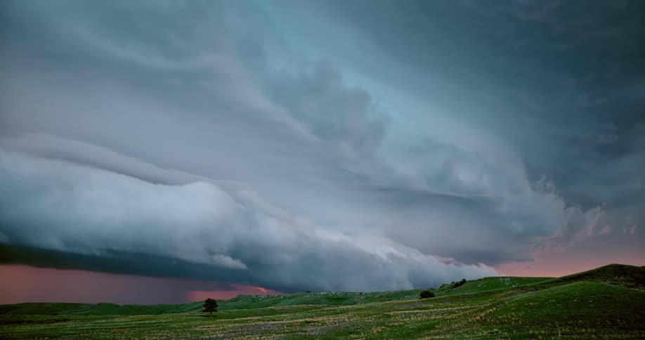 Lightning flashes from within an enormous layer of storm clouds that are hovering above the ground