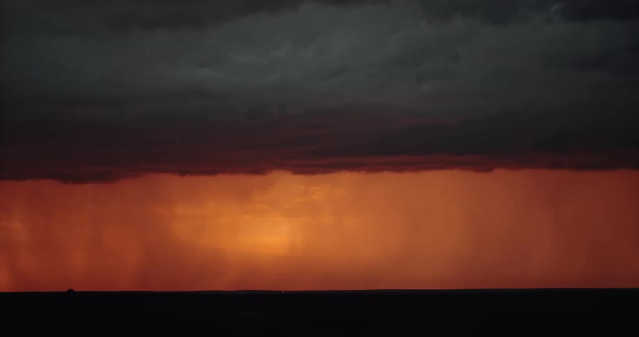 Lighting illuminating an orange sky during a rainstorm