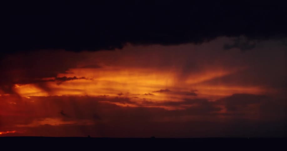 Lightning flashes across a red sky during a storm at night
