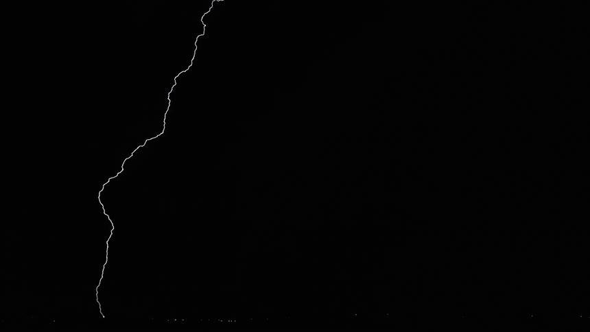 Lightning bolts flash and branch out in a dark sky