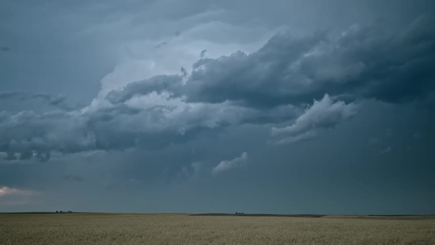 Lightning flashes in a dark cloudy sky over a field