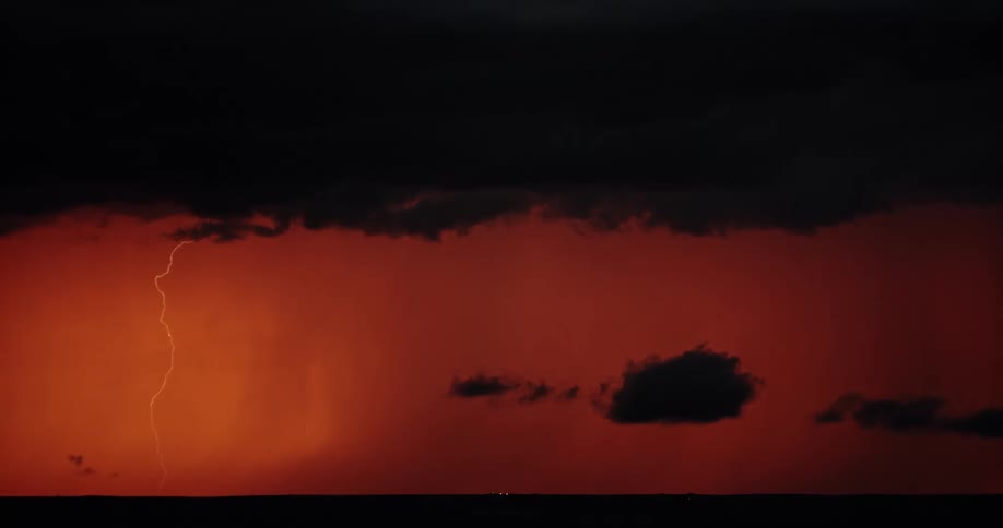 Lightning flashes in an orange glowing sky