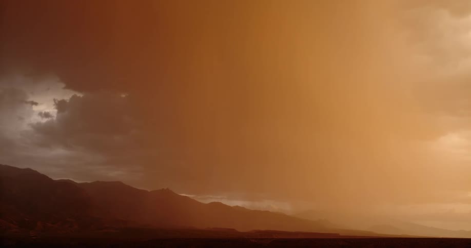 Lightning bolts come down near mountains under an orange stormy sky