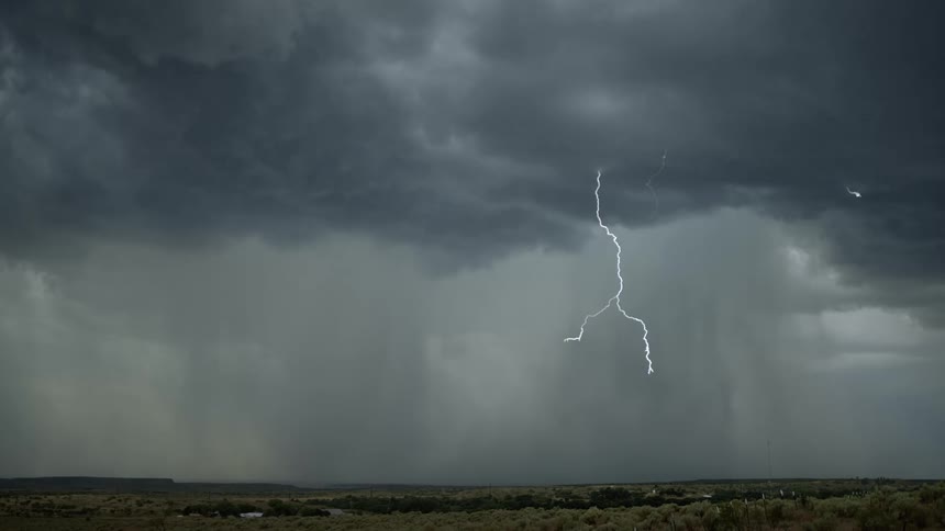 Lightning streaking arcs flashing across storm clouds over a field
