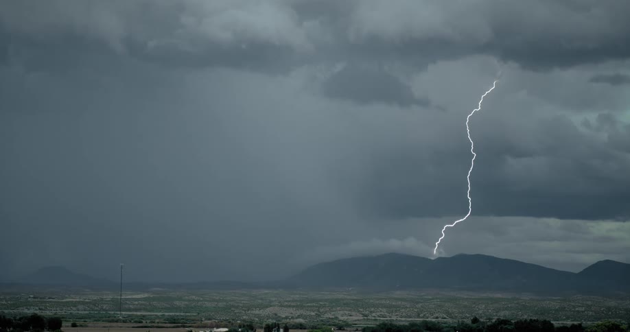 A powerful bolt of lightning shoots downward from the sky and strikes the ground during a storm