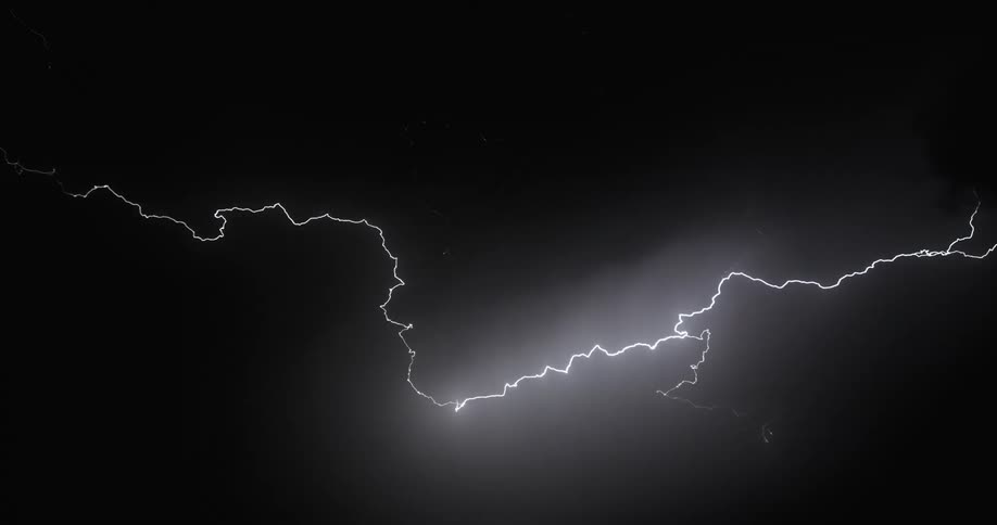 Lightning streaking arcs flashing over the silhouette of black clouds at night