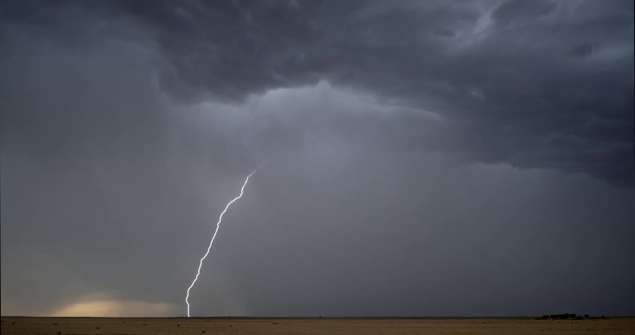 Lightning bolts from a dark storm cloud flash in the sky