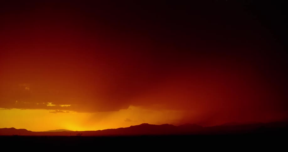 Lightning streaking arcs flashing across yellow and red storm clouds over a field
