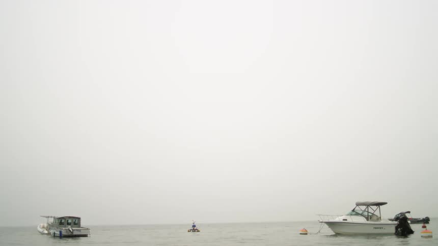 Boats on ocean water with the sky and clouds in the background