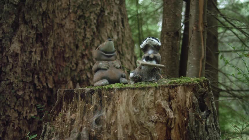 Two animal statues on a mossy tree trunk in a forest