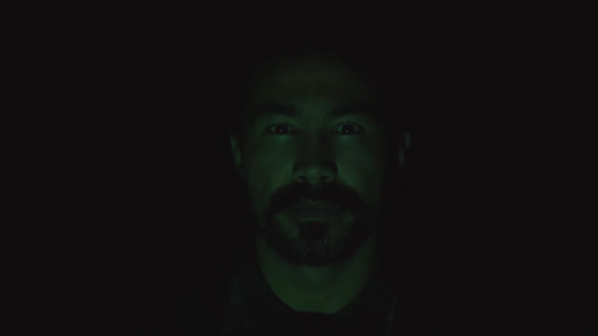 A red digital line scans across a mans face in the dark and the word positive appears on his forehead