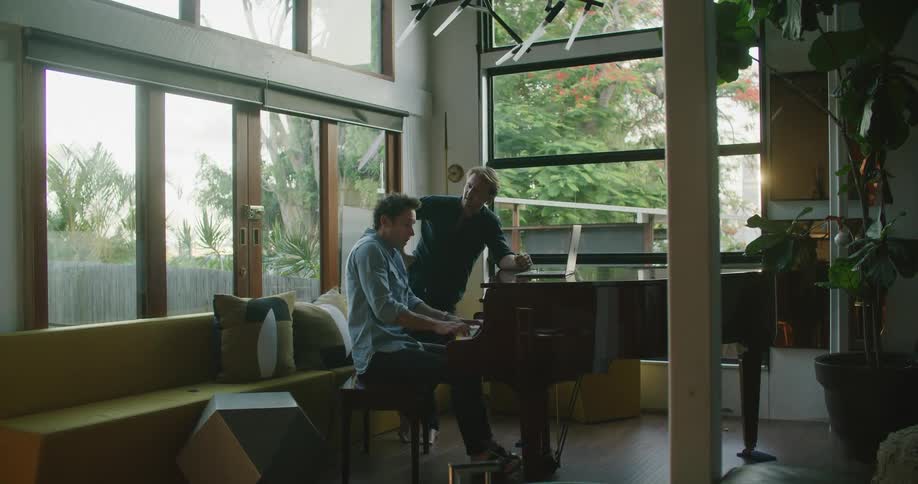Two men are playing the piano indoors