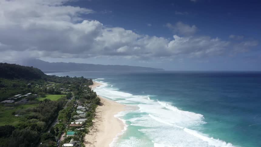 Aerial view of a small town in the coast of a tropical beach near the mountains at sunset