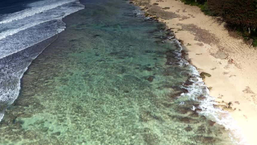 Aerial view of the coastline of a tropical beach near a smal town at daytime