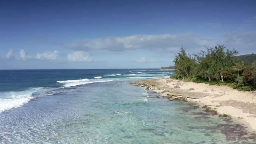 Aerial view of the blue ocean water waves crashing on the coast