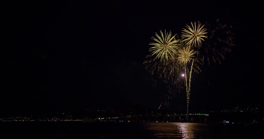 Fireworks show over a small town near a river at night