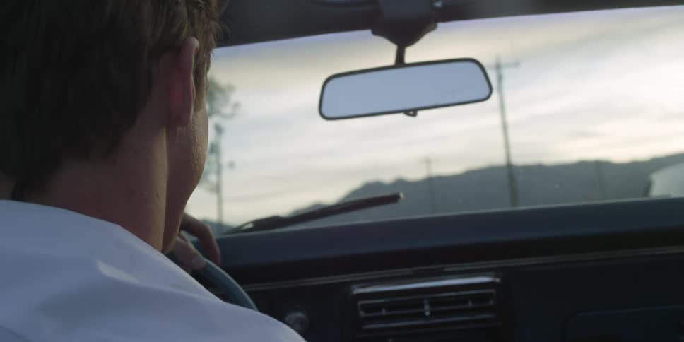 Couple exchange kisses while driving a car on a rural road