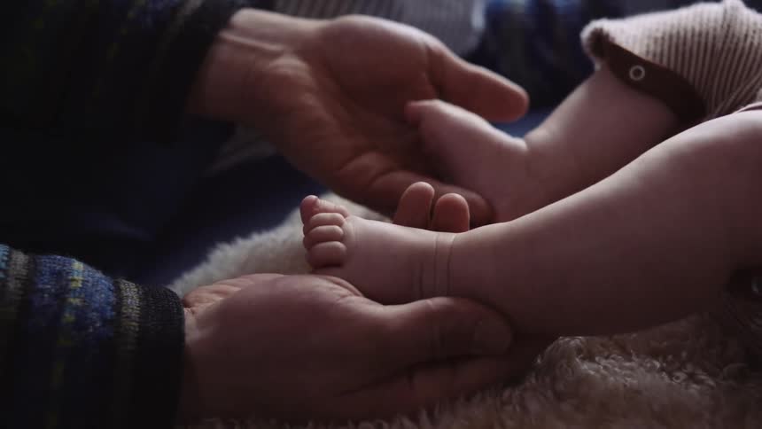 A man cradling a babys bare feet