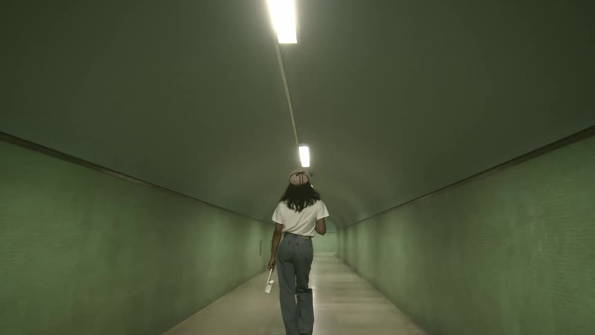 A woman holding a small white purse walking inside of tunnel with lights