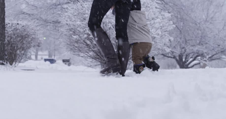 A woman walks a boy in heavy snow