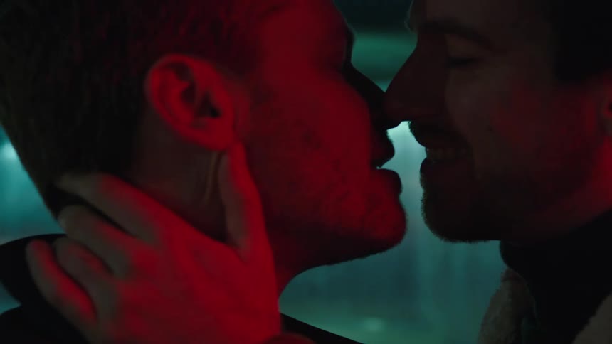 Two men are kissing outdoors at night