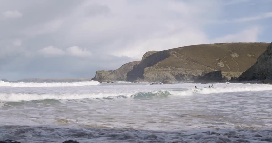 A group of surfers waiting for waves in the coast near the mountain