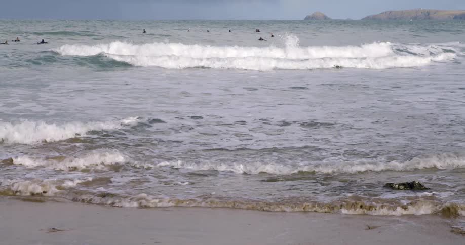 Surfers swim in the sea on a cloudy day