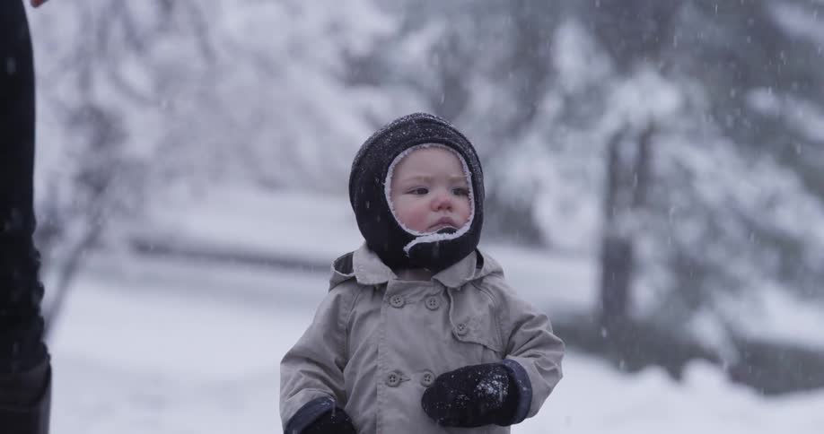 A child looks unhappy standing outside in the snow