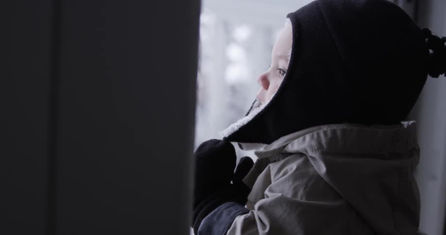 A child is pressed against the window looking out