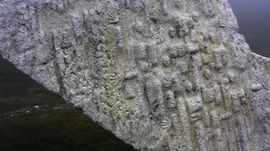 Large stone artwork with sculpted faces outdoors