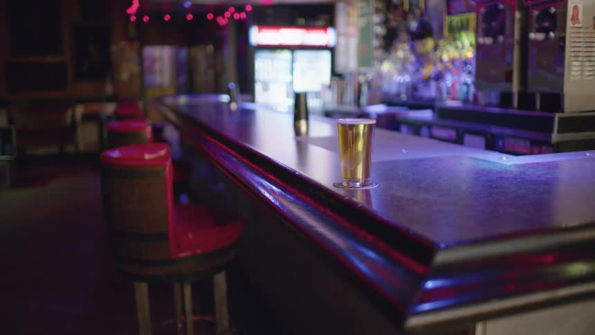 A glass of beer served over a coaster in the empty bar on a pub