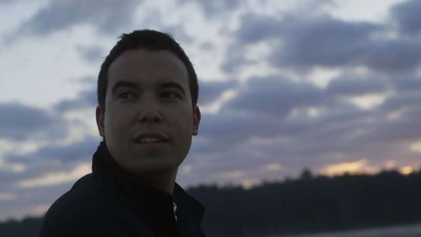A man standing near a body of water at dawn