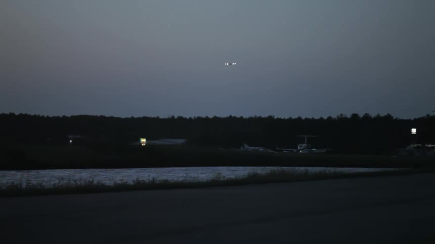 A plane flies over a lake at night