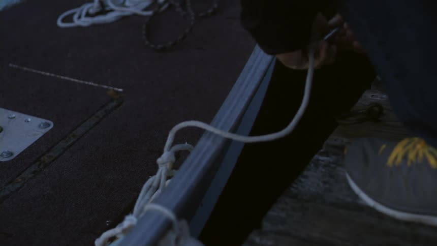 A person unties a boat from a dock