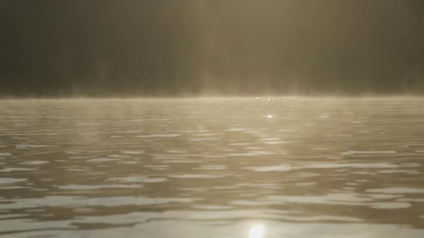 Sunlight reflects off a a mist-covered lake