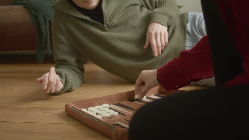 Young couple playing backgammon on the floor of the living room