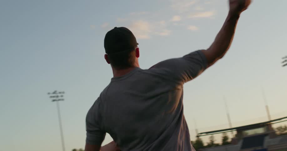 A man with muscular arms throws a baseball to another during a game of catch