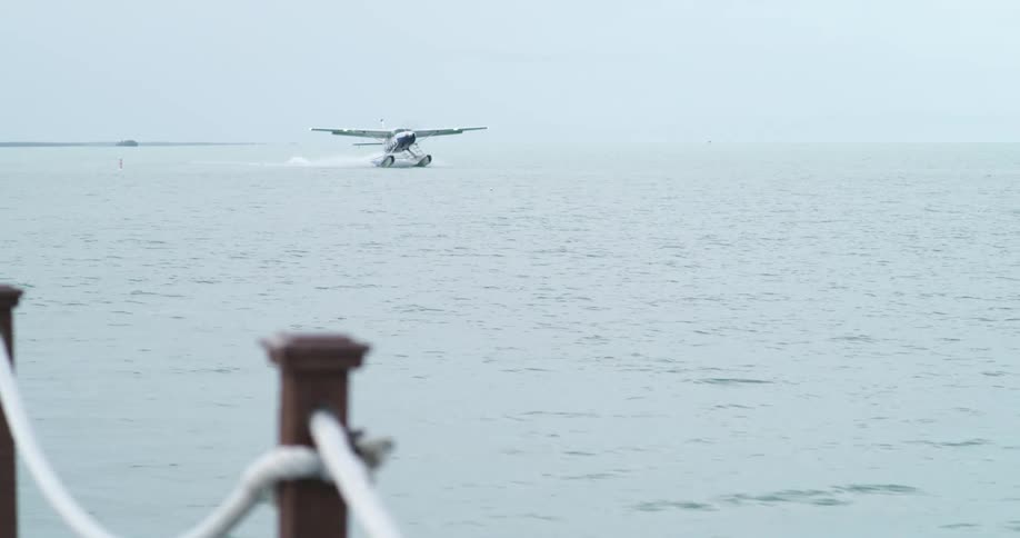 An airplane landing on a body of water with the sky and clouds in the background