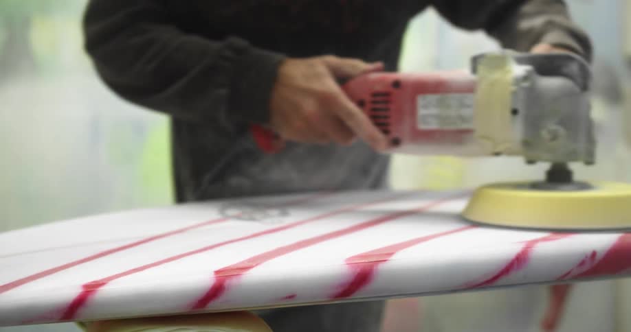 A man sands a surfboard