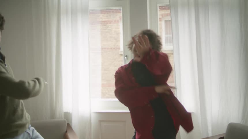 Couple dances in living room near window