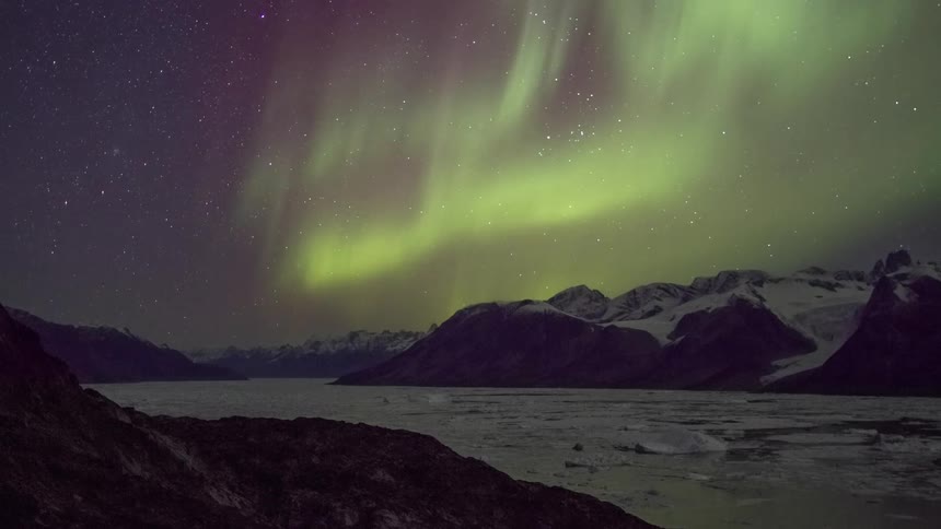 Aurora borealis shining brightly above snow covered mountains