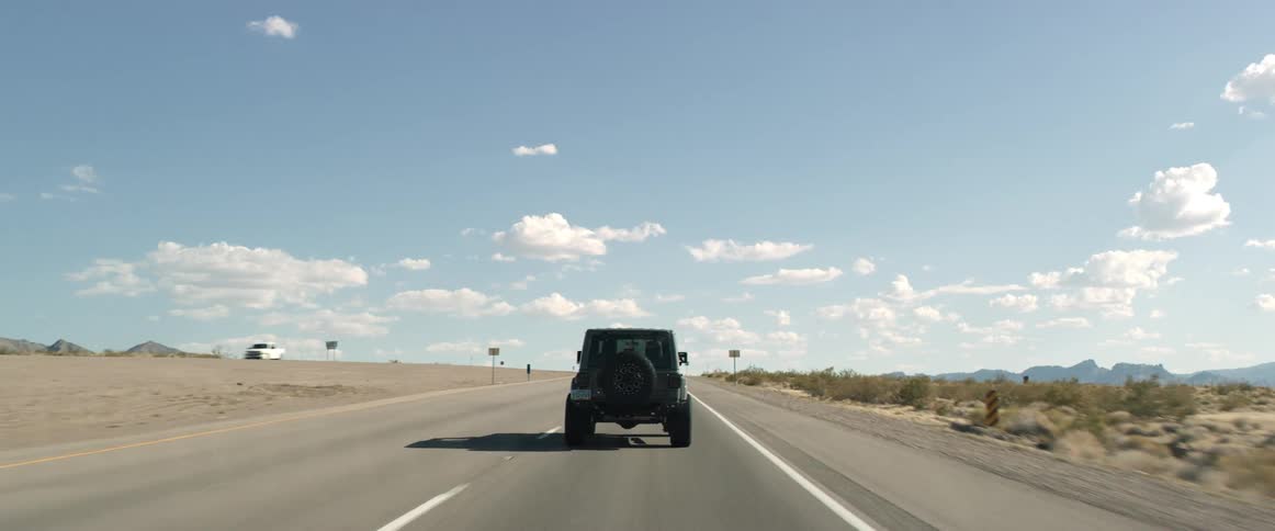 Jeep driving along a highway through the desert at midday