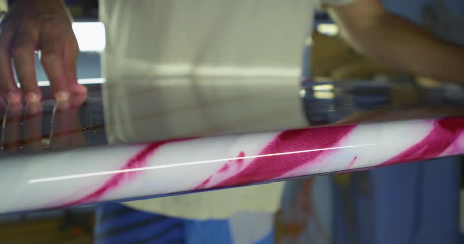 A person in a room wiping a surfboard with a cloth