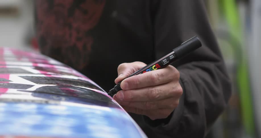 A person marking a surfboard with a marker